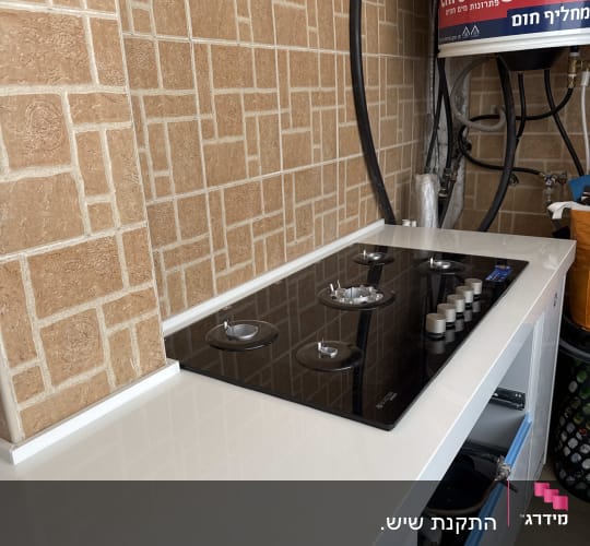כיריים על משטח עבודה עם רקע קיר מרוצף